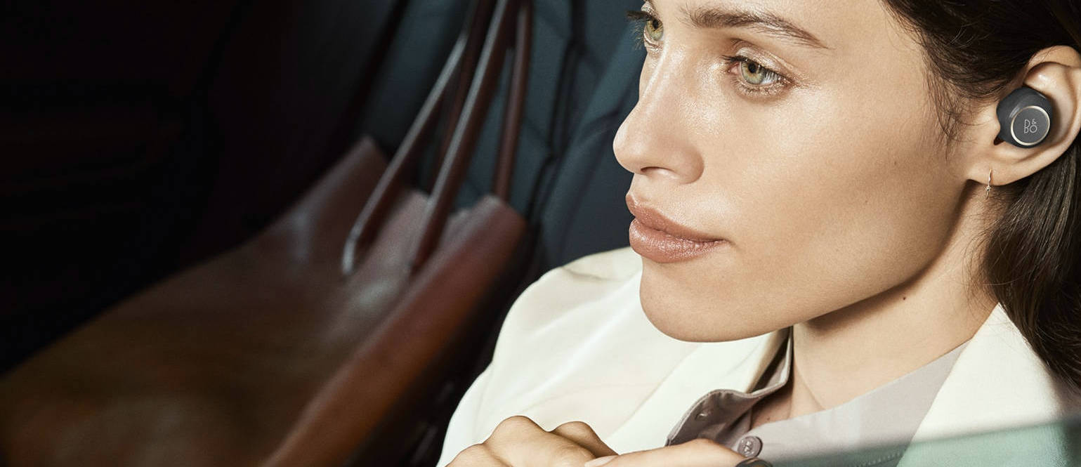 A woman with a B&O e8 in her left ear.